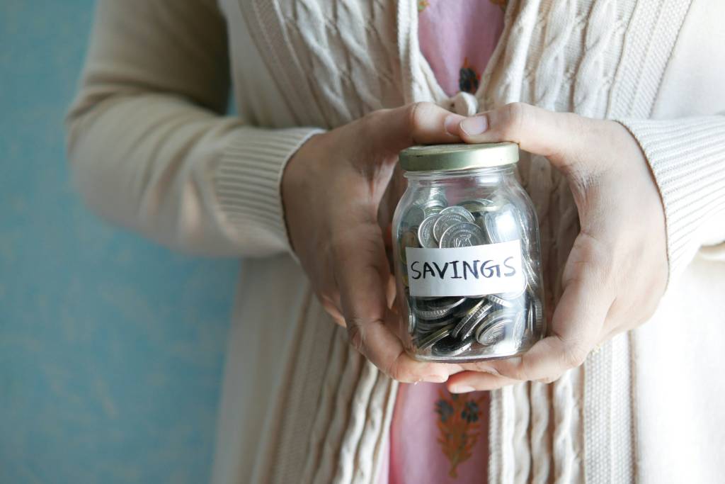 Woman holding savings jar with coins